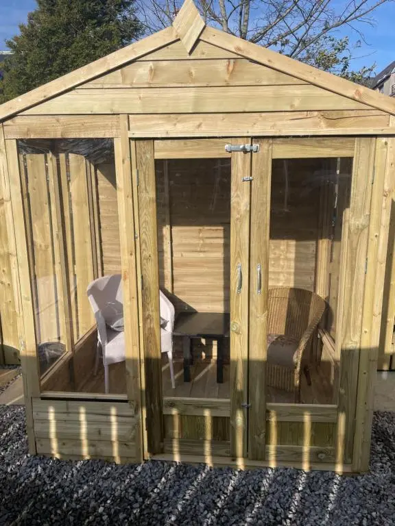 a wooden gazebo with a table and a chair at Garden Room at Tartan House in Inverness