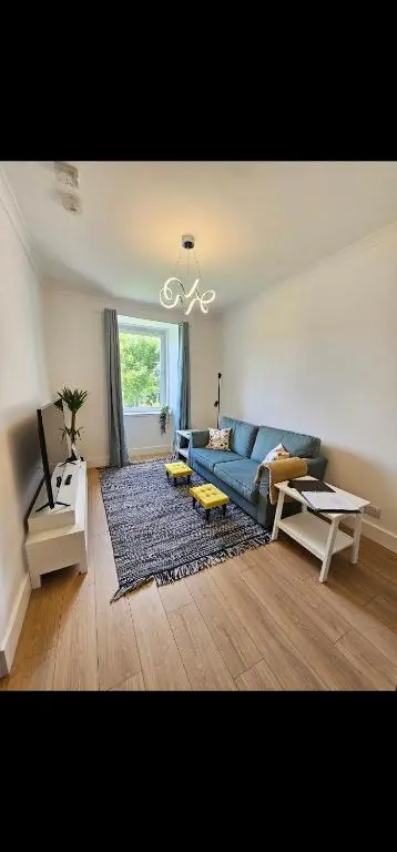 a living room with a blue couch and a table at Inverness City Centre Modern Apartment in Dalneigh
