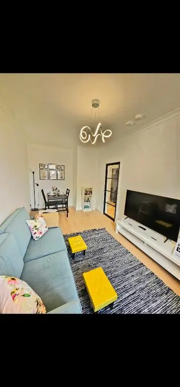 a living room with a blue couch and a flat screen tv at Inverness City Centre Modern Apartment in Dalneigh