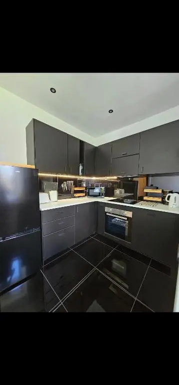 a large kitchen with black cabinets and appliances at Inverness City Centre Modern Apartment in Dalneigh