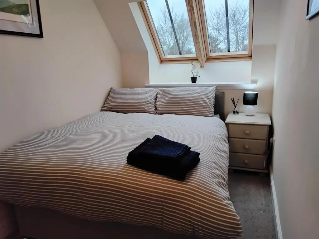 a bedroom with a bed with a black bag on it at Turfhill House in New Deer