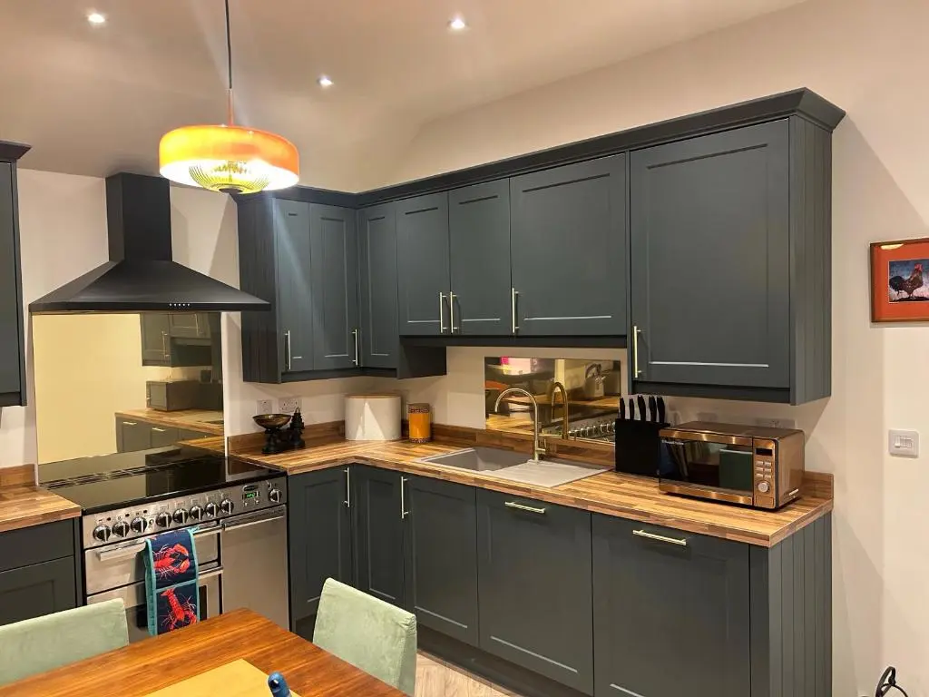 a kitchen with black cabinets and a wooden table at Calsie Cottage, Clatt in Kirktown of Clatt