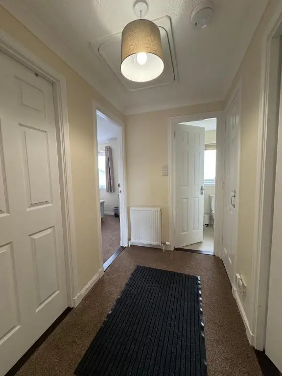 an empty hallway with a door and a rug at Comfortable double room with own bathroom in Inshes