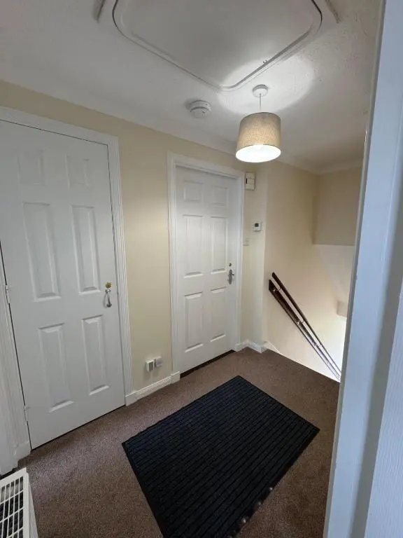 an empty room with a white door and a black rug at Comfortable double room with own bathroom in Inshes