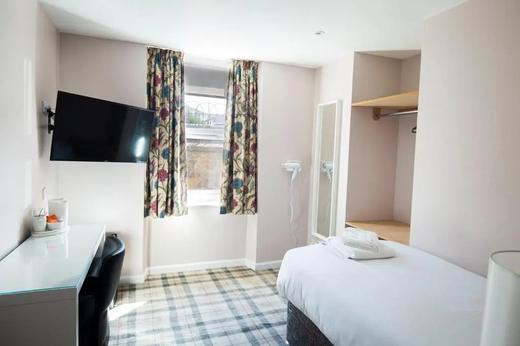 a hotel room with a bed and a desk and a window at Poseidon's in Lossiemouth