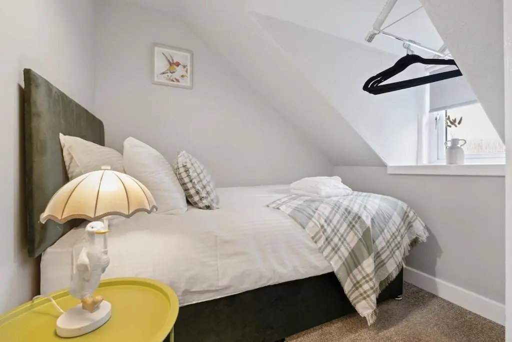 a bedroom with a bed and a yellow table at Leo Apartment - 4 Bedroom Flat in Nairn in Nairn