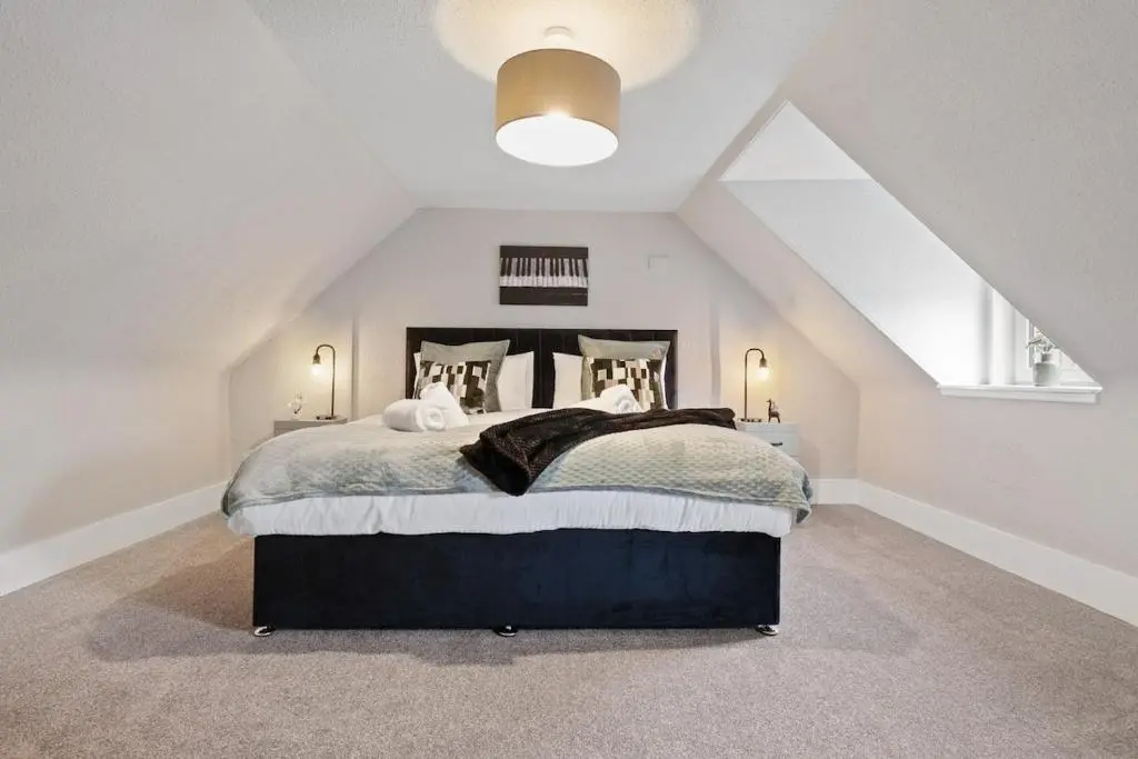a bedroom with a large bed in a attic at Leo Apartment - 4 Bedroom Flat in Nairn in Nairn