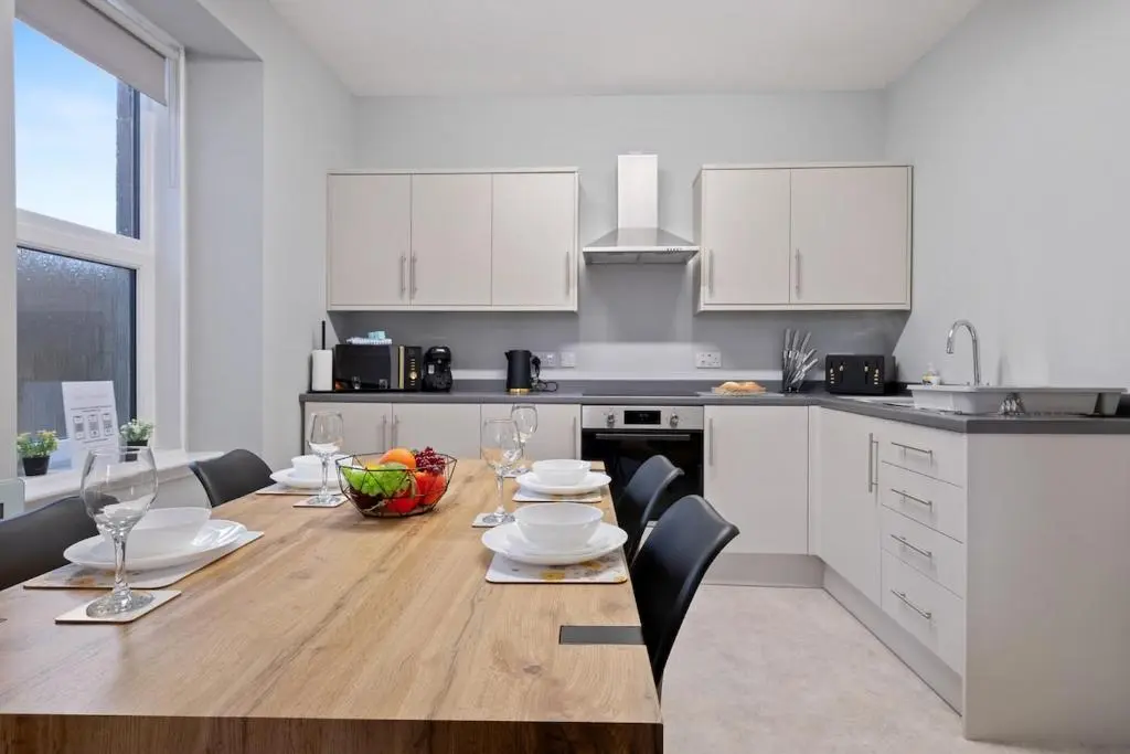 a kitchen with a wooden table with chairs and a dining room at Leo Apartment - 4 Bedroom Flat in Nairn in Nairn