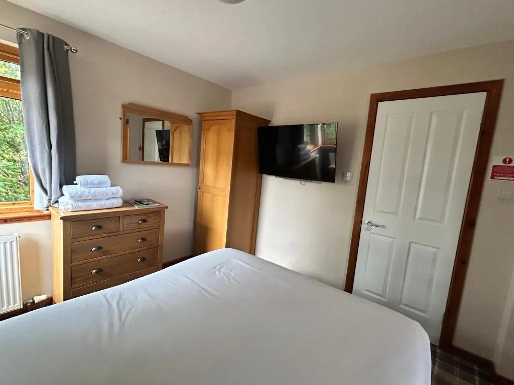a bedroom with a bed and a dresser and a television at Westend Hotel & Bar in Nairn