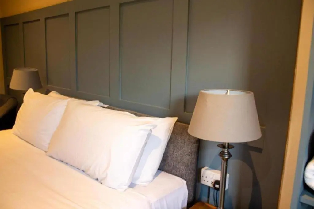 a bedroom with a bed with white pillows and a lamp at Westend Hotel & Bar in Nairn