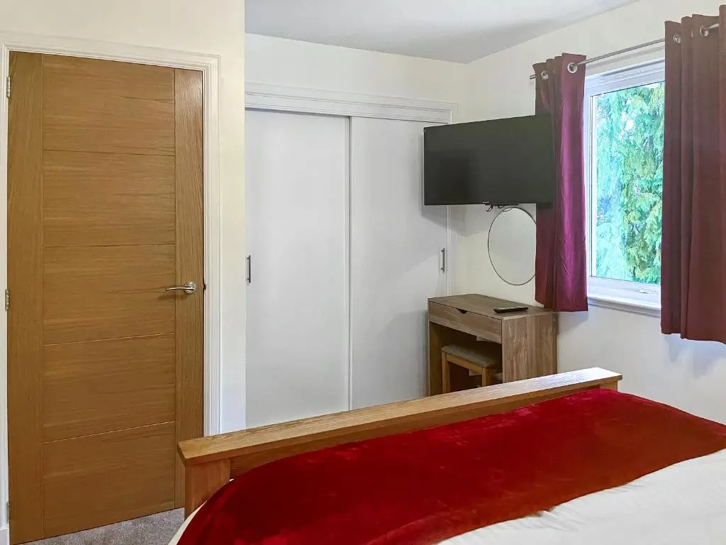 a bedroom with a bed with a red blanket and a window at Dee View Apartment in Banchory