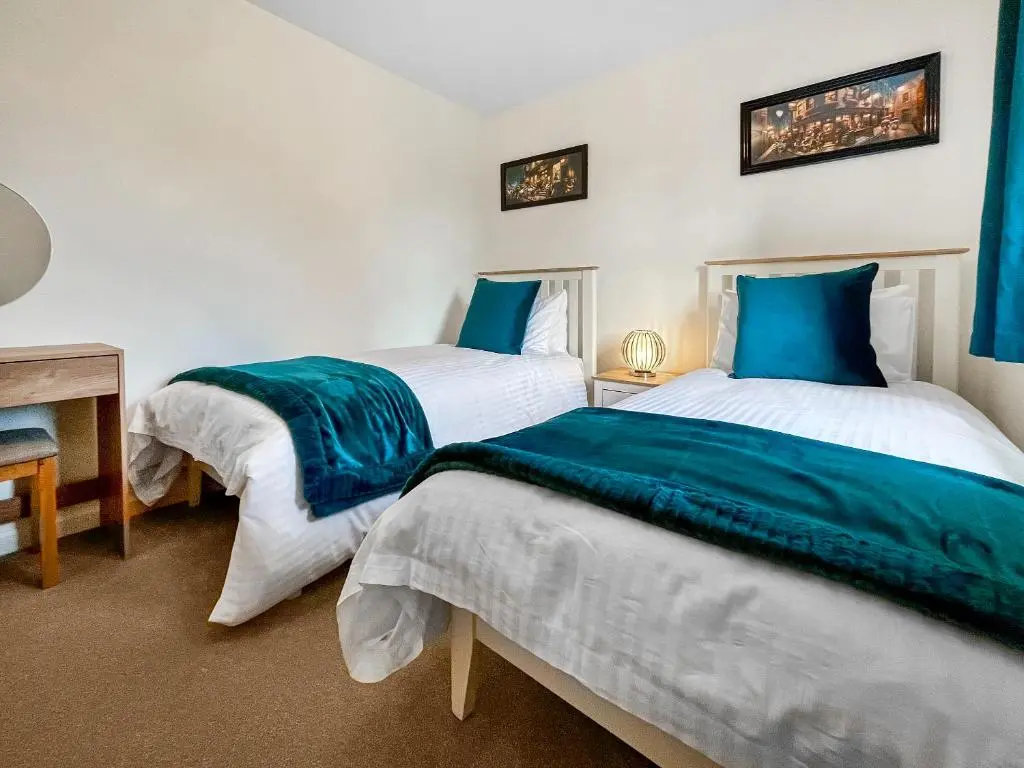 two beds in a room with blue and white at Dee View Apartment in Banchory