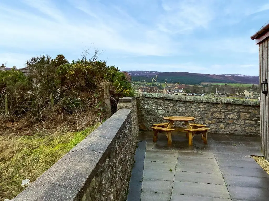 a table and two benches on a stone wall at Mirodon in Brora