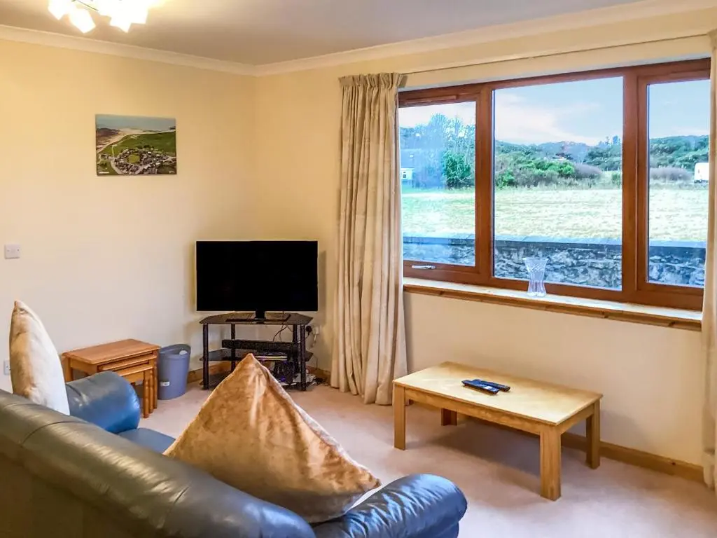 a living room with a leather couch and a television at Mirodon in Brora