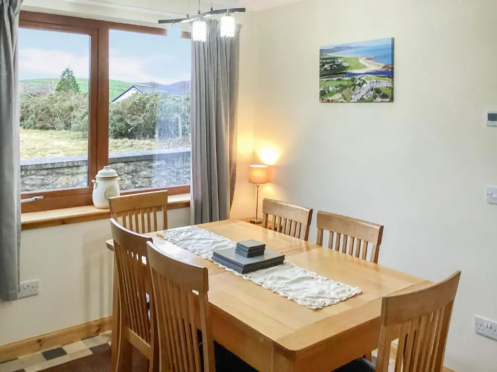 a dining room with a table and chairs and a window at Mirodon in Brora