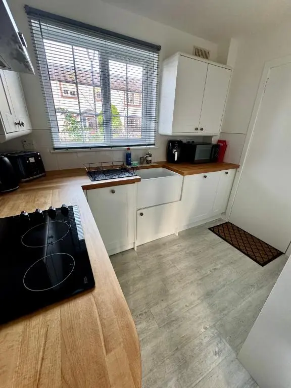 a kitchen with white cabinets and a wooden counter top at Culduthel Court Apartment in Inshes