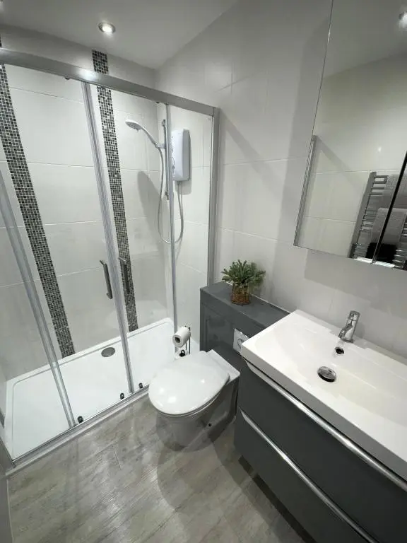 a bathroom with a shower and a toilet and a sink at Culduthel Court Apartment in Inshes