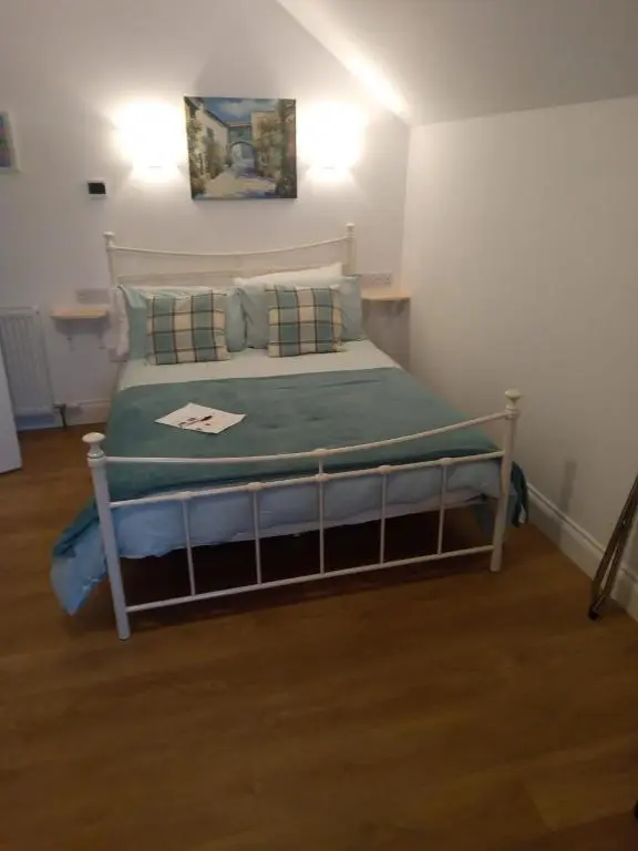 a bedroom with a bed with a green blanket and pillows at Atherstone B&B in Inverness