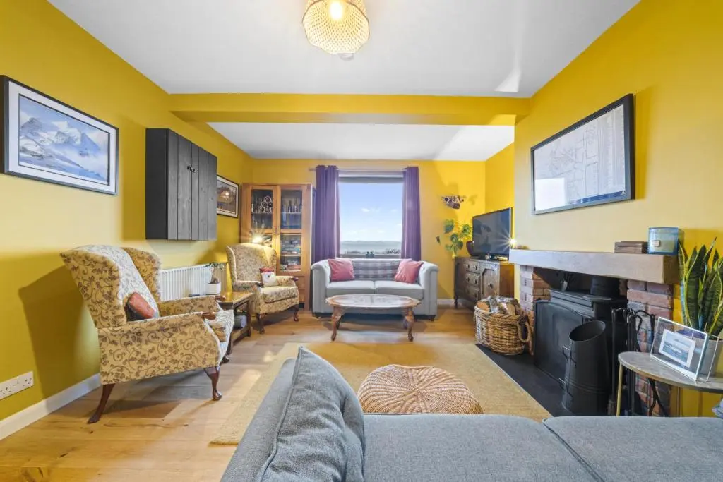 a living room with yellow walls and a fireplace at Beinn View 3 Bedroom House - Sea View - Ardersier in Ardersier