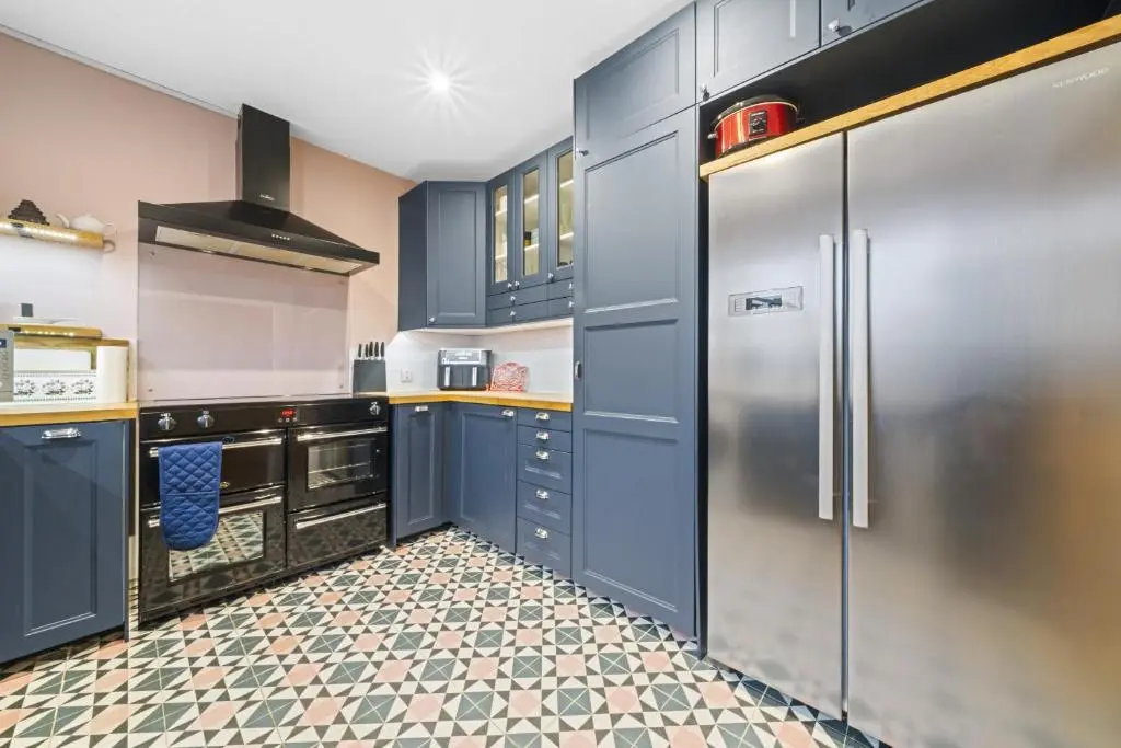a kitchen with blue cabinets and a stainless steel refrigerator at Beinn View 3 Bedroom House - Sea View - Ardersier in Ardersier