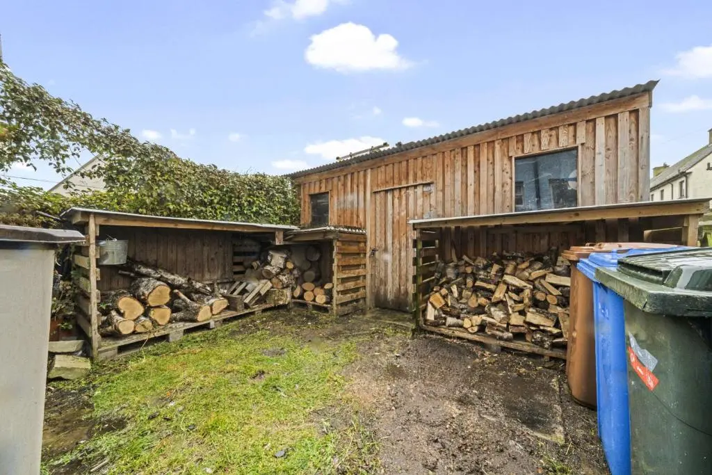 a wooden building with a pile of fire wood at Beinn View 3 Bedroom House - Sea View - Ardersier in Ardersier