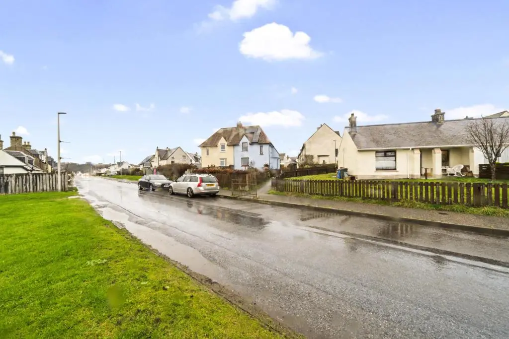 two cars parked on a wet street with houses at Beinn View 3 Bedroom House - Sea View - Ardersier in Ardersier
