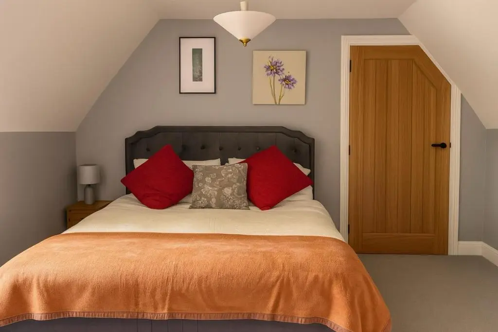 a bedroom with a bed with orange sheets and red pillows at Overscaig House in Lairg