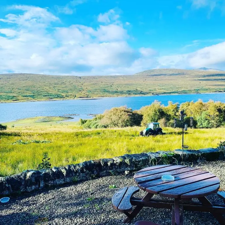 a picnic table sitting on the side of a lake at Overscaig House in Lairg