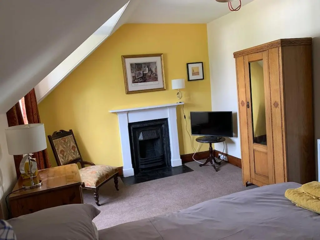 a bedroom with a fireplace and a bed and a television at Glenerne 3 bedroom Cottage in Elgin
