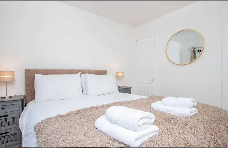 a white bedroom with a large bed with towels on it at 2 Bedroom Macewen Drive in Inverness