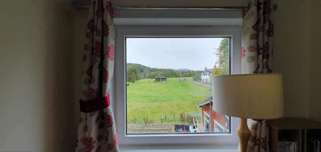 a window with a view of a green field at River View in Garve