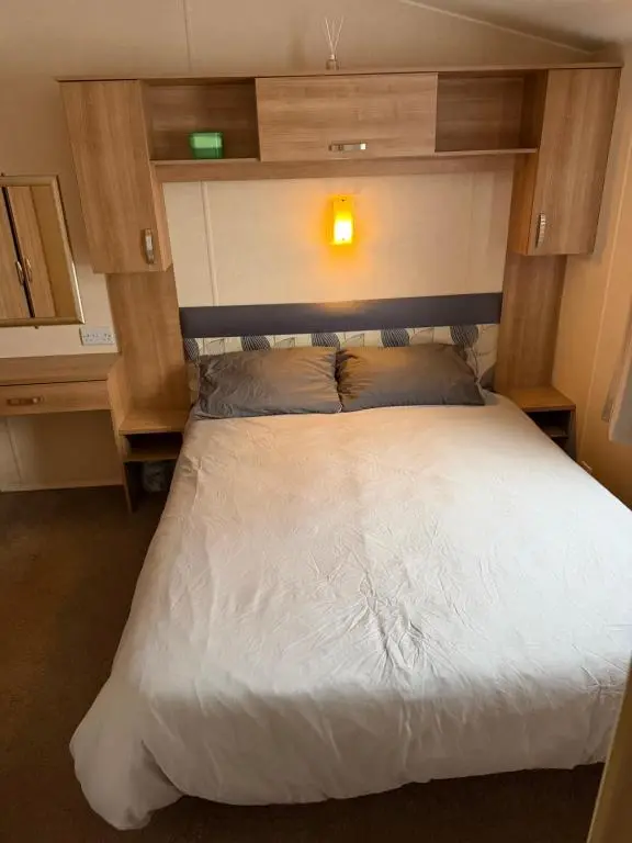 a bedroom with a white bed with a light above it at Casa MALC Caravan in Lossiemouth