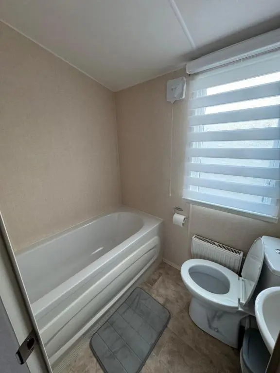 a bathroom with a tub and a toilet and a sink at Casa MALC Caravan in Lossiemouth