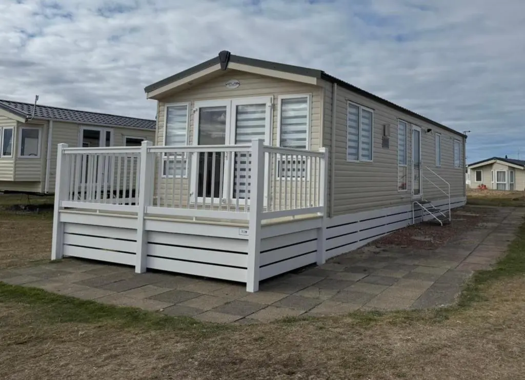 a tiny house with a porch and a white railing at Casa MALC Caravan in Lossiemouth