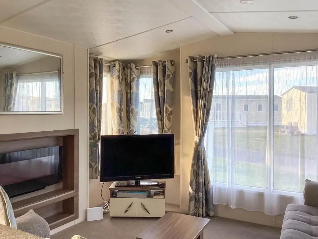 a living room with a flat screen tv next to a window at A Stone's Throw in Lossiemouth