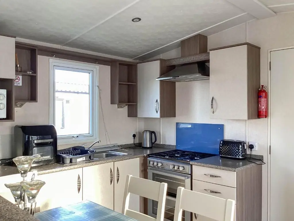 a kitchen with a stove and a table with chairs at A Stone's Throw in Lossiemouth