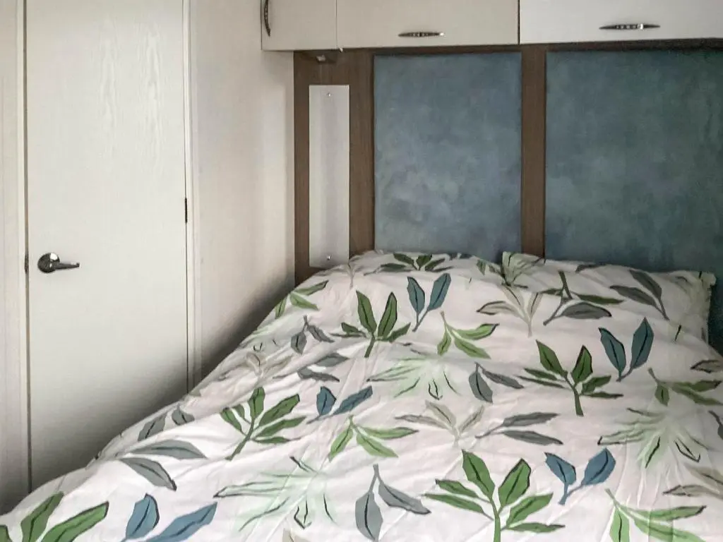 a bed in a bedroom with a bedspread with leaves on it at A Stone's Throw in Lossiemouth