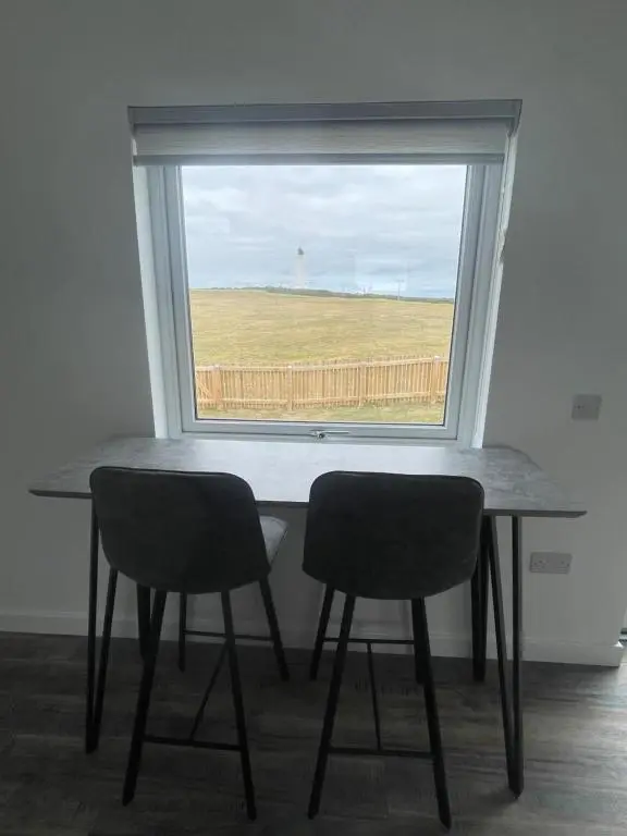 a table and two chairs in a room with a window at 1 Lighthouse View in Lossiemouth