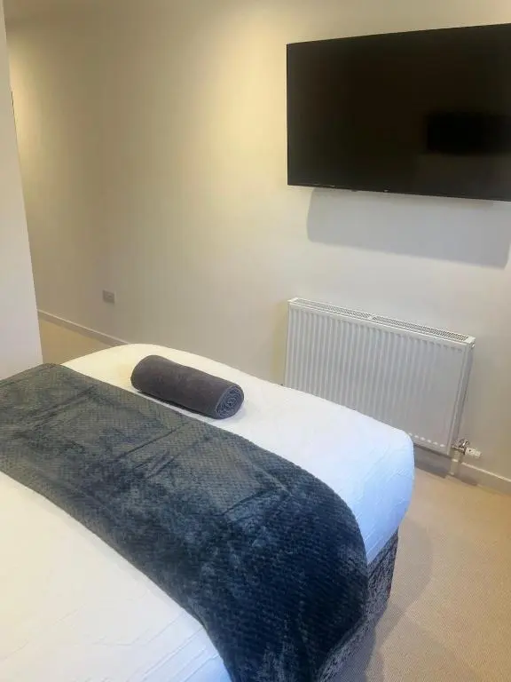 a bed with a black blanket and a flat screen tv at Newly Renovated Luxuary Flat overlooking Wick Bay in Wick