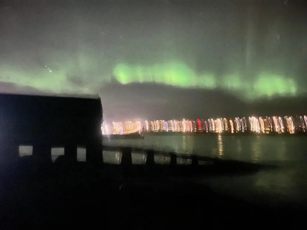 a person standing next to a truck under the aurora at Newly Renovated Luxuary Flat overlooking Wick Bay in Wick