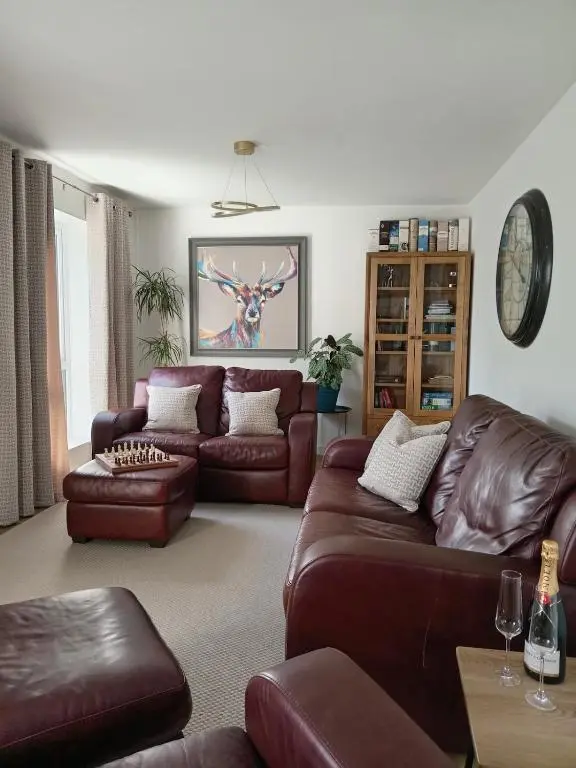 a living room with brown leather couches at Modern 4 Bed Highland Home in Culloden