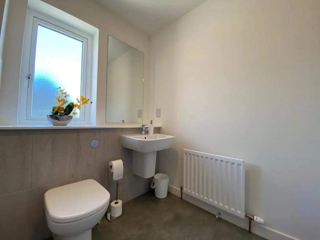 a bathroom with a toilet and a sink and a window at Modern 4 Bed Highland Home in Culloden
