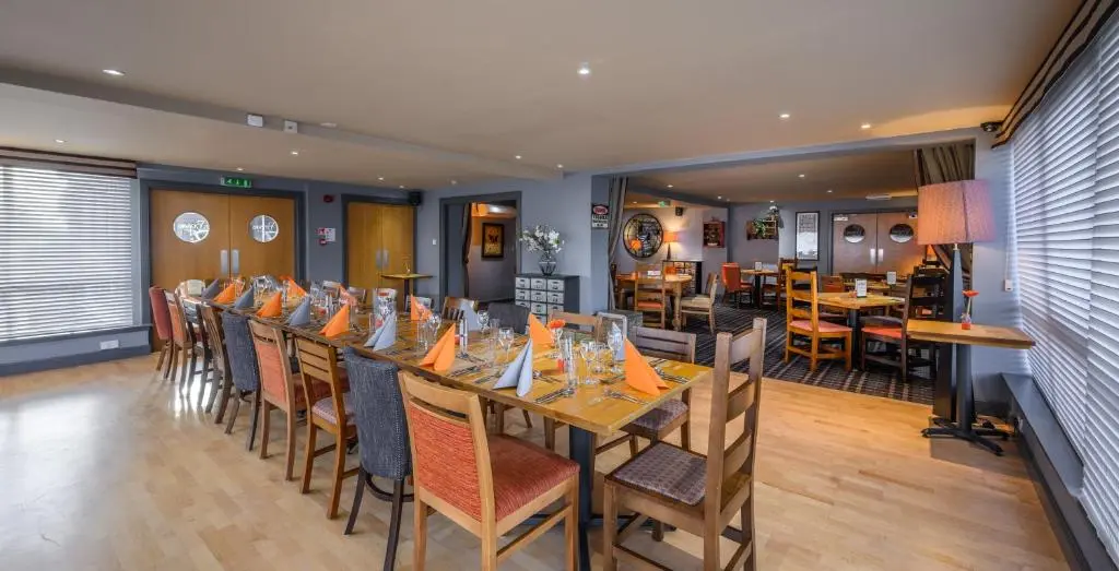 a long dining room with a long table and chairs at The Dunavon in Dyce