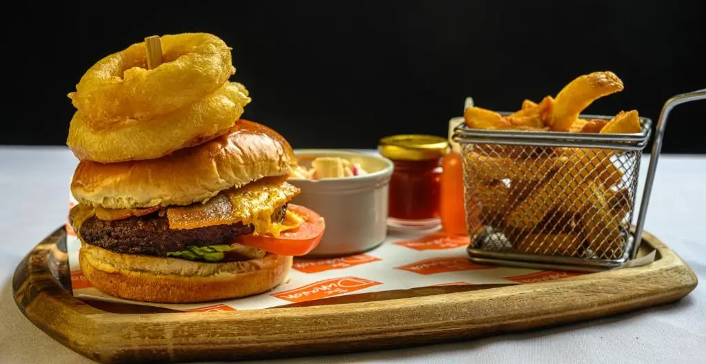 a hamburger with onion rings and a basket of fries at The Dunavon in Dyce