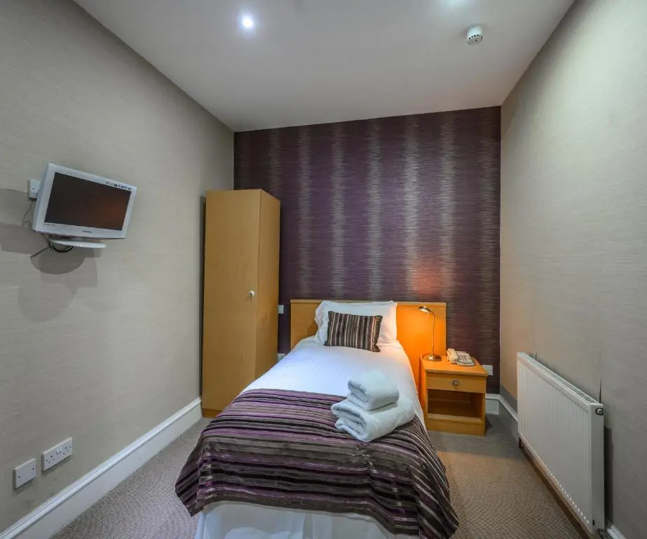 a bedroom with a bed and a tv on the wall at The Dunavon in Dyce