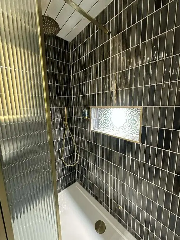 a bathroom with a shower with a tub and a window at Modern central apartment in Wick
