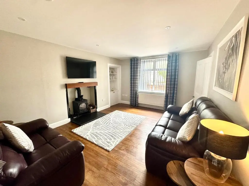 a living room with a leather couch and a fireplace at City Centre 3 Bedroom house with parking in Dalneigh