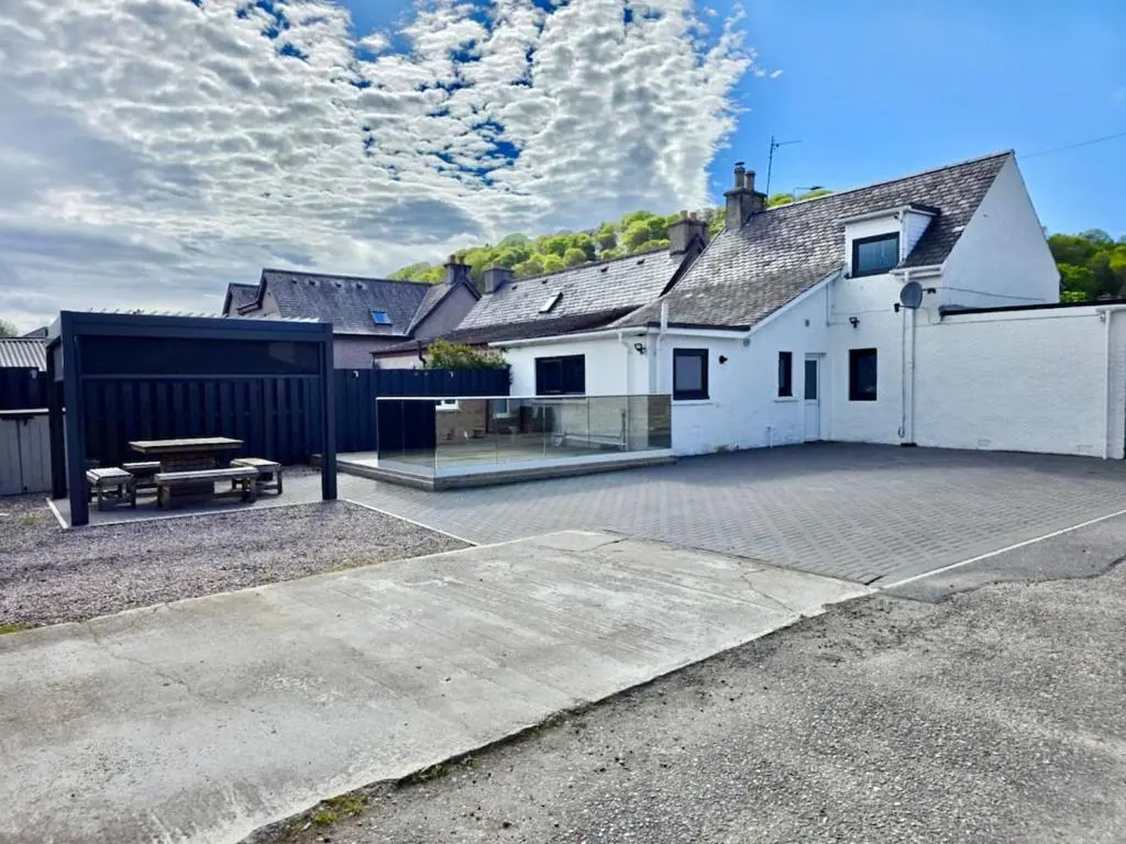 a large white house with a bench in a parking lot at City Centre 3 Bedroom house with parking in Dalneigh