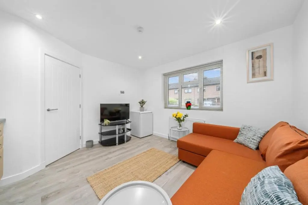 a living room with an orange couch and a tv at Temple 1 Bedroom Studio - Inverness in Inverness