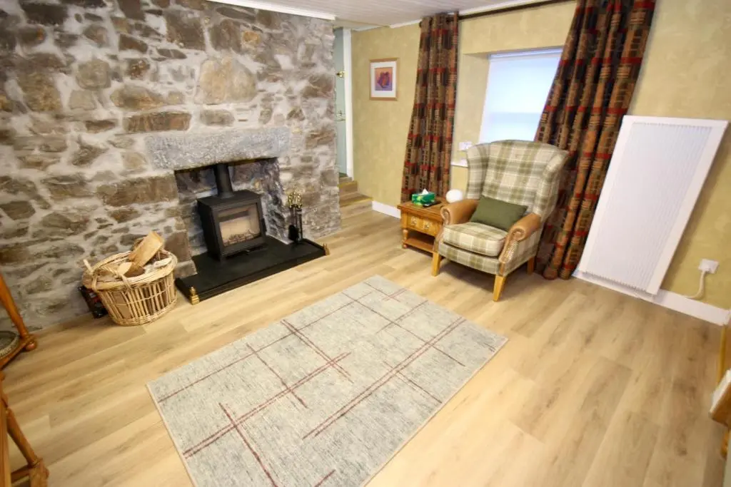 a living room with a stone fireplace and a chair at Serenity by the Sea in Buckie